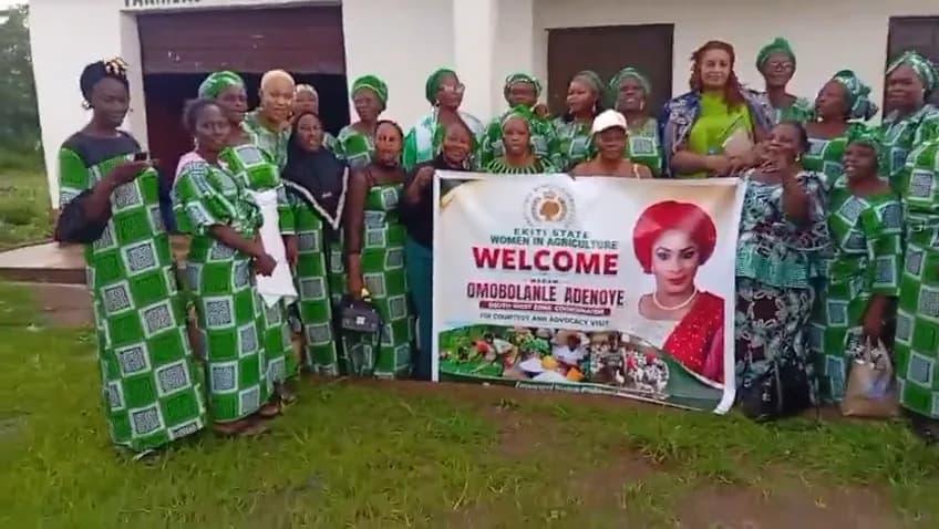 Ekiti women in green uniforms gathered around a banner welcoming the President.