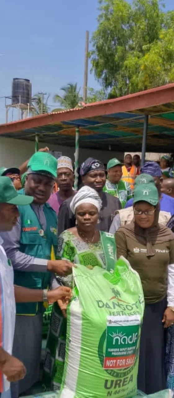 Women farmers in green caps receiving a bag of fertiliser.
